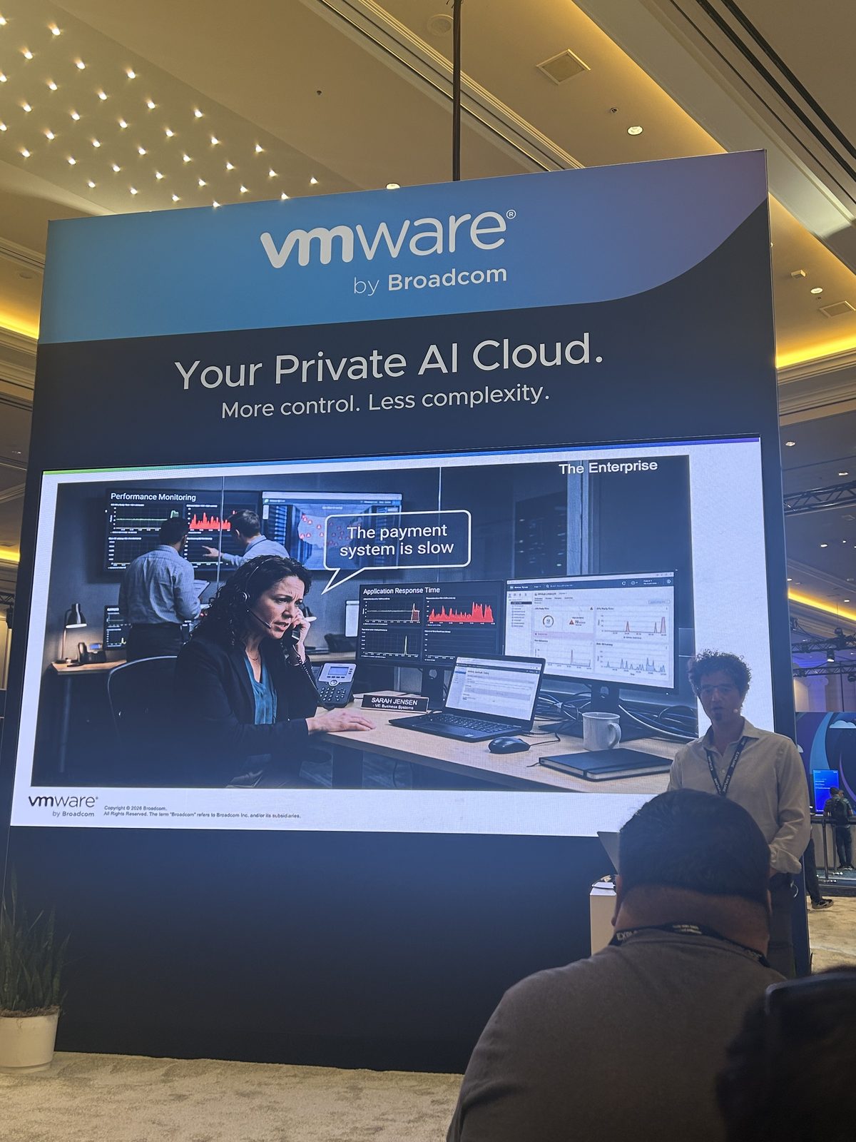 A large vendor booth display showing an operations center scene with a support worker on the phone and a speech bubble reading the payment system is slow